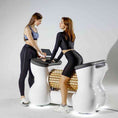 Load image into Gallery viewer, Two women using a futuristic medical examination table in a clinical setting.