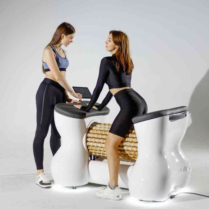 Two women using a futuristic medical examination table in a clinical setting.