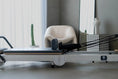 Load image into Gallery viewer, Reformerc fitness machine in a modern room with a chair and plant.
