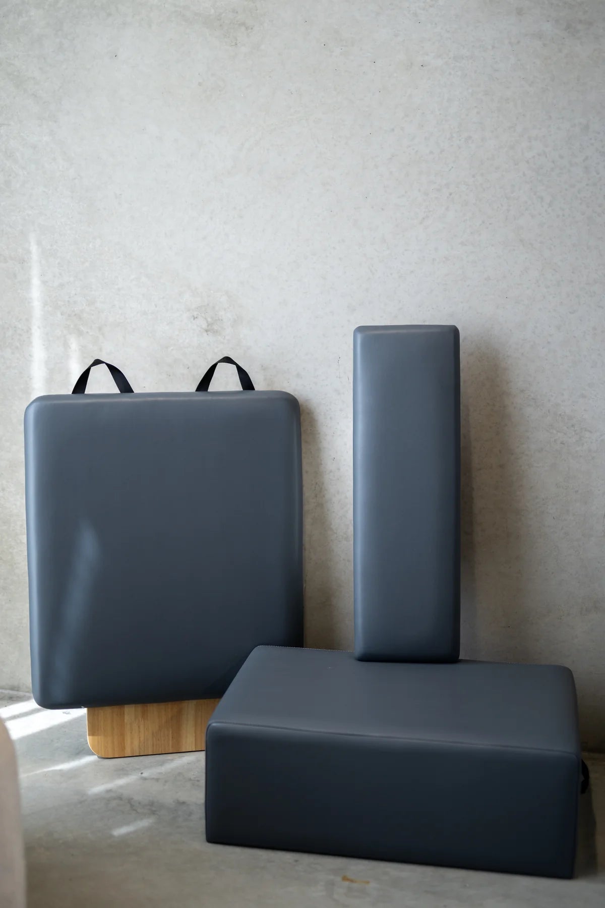 Three gray foam blocks with handles on a light gray background